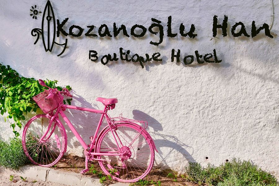 pink bicycle resting on the white wall charming exterior of kozanoglu han boutique hotel alacati turkey