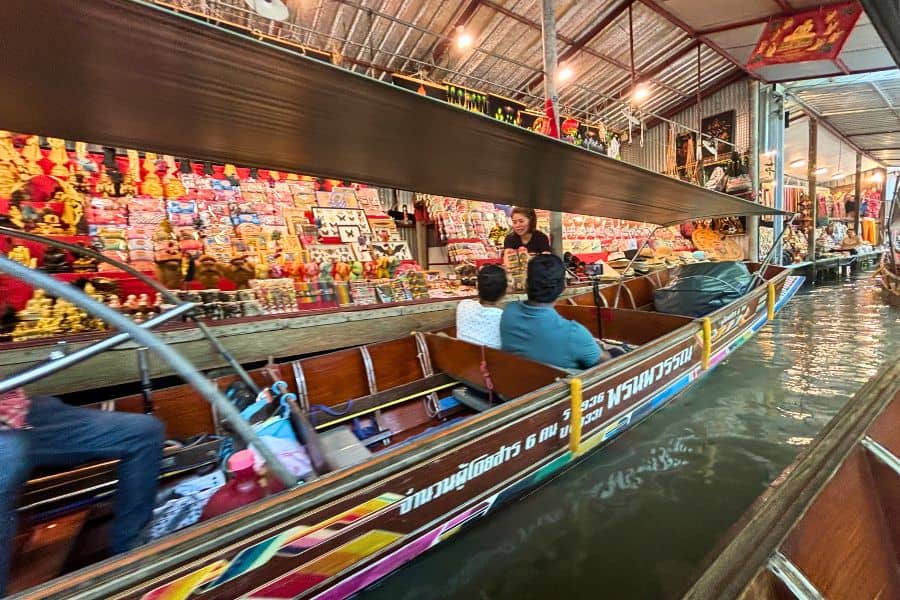 tourists in boats shopping at stalls at damnoen saduak floating market near bangkok