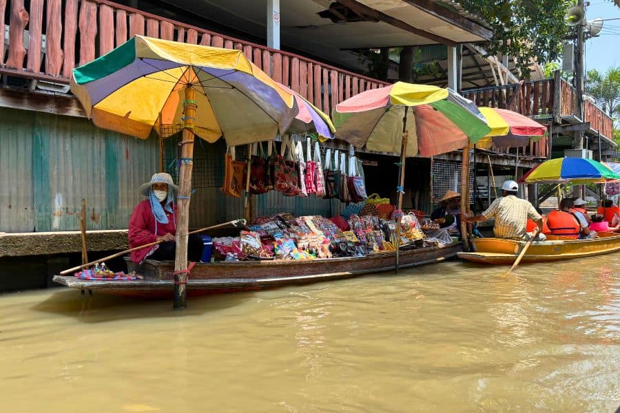 vendors selling items or souvenirs in their boats at damnoen saduak floating market