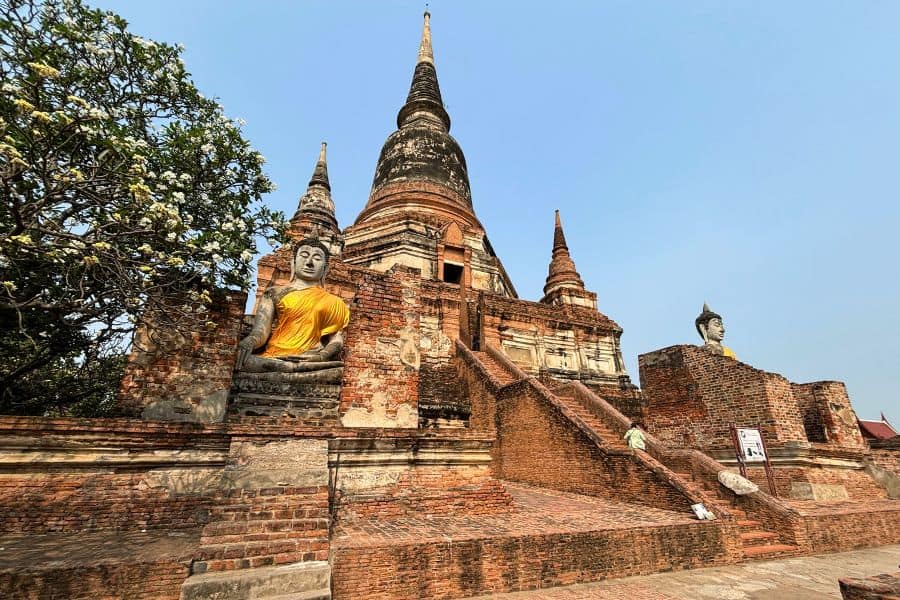 wat yai chai mongkhon in ayutthaya, thailand, featuring ancient stupas and buddha statues surrounded by lush greenery