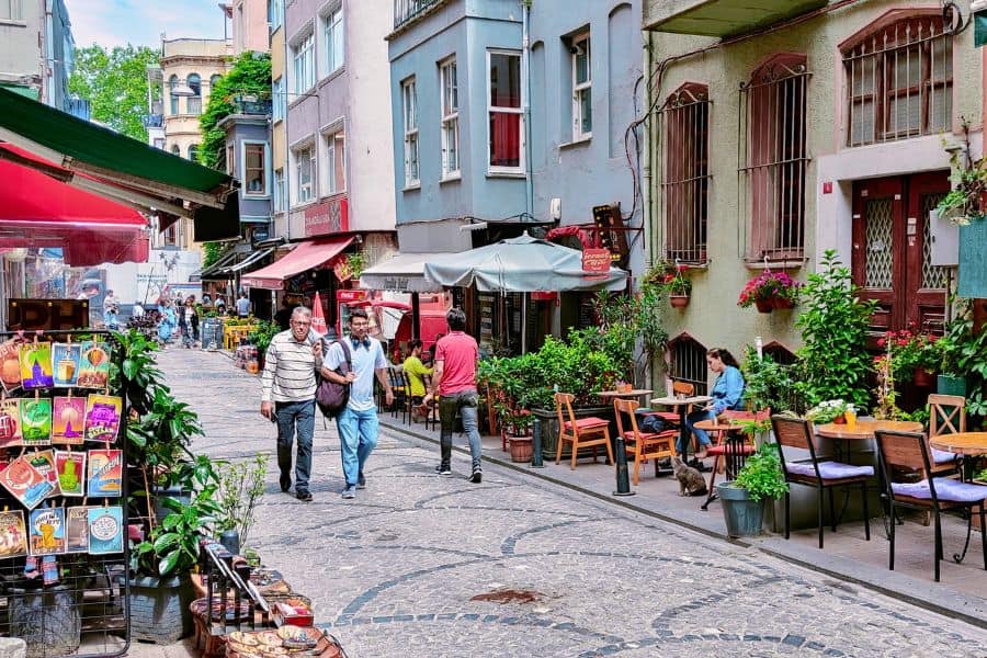 a charming street in istanbul's fatih district with cafes, plants, and people strolling