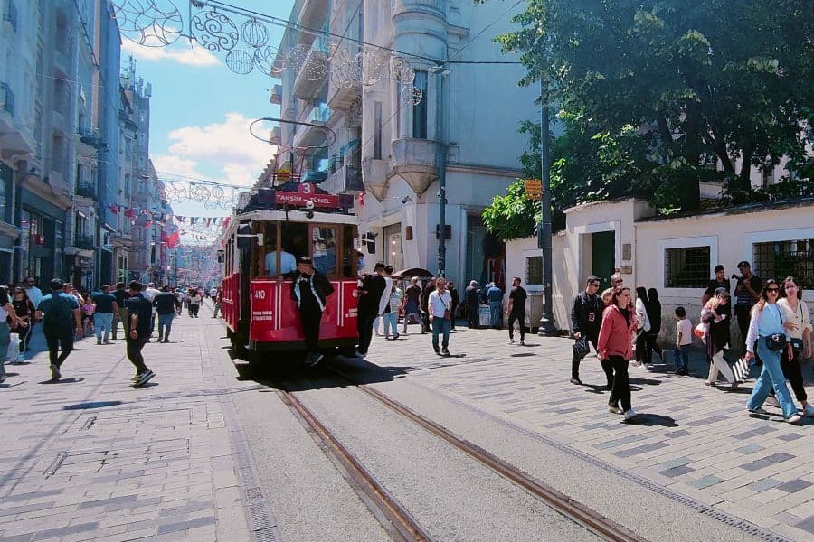 a red tram on istiklal street in istanbul with people walking along the lively street