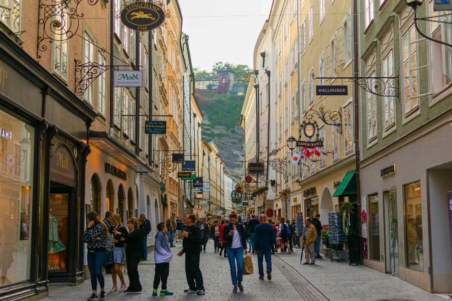 people walking a beautiful historic street in salzburg called getreidegasse