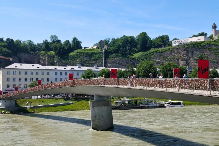 people crossing salzach river via makarsteg footbridge aka marko-feingold-steg aka love lock bridge in salzburg
