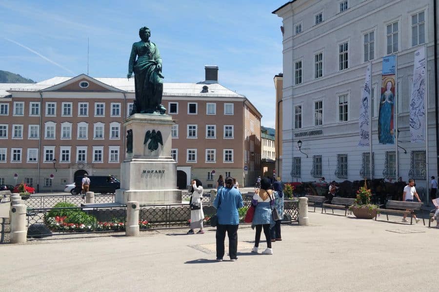 people gawking at the mozart monument in the center of mozartplatz