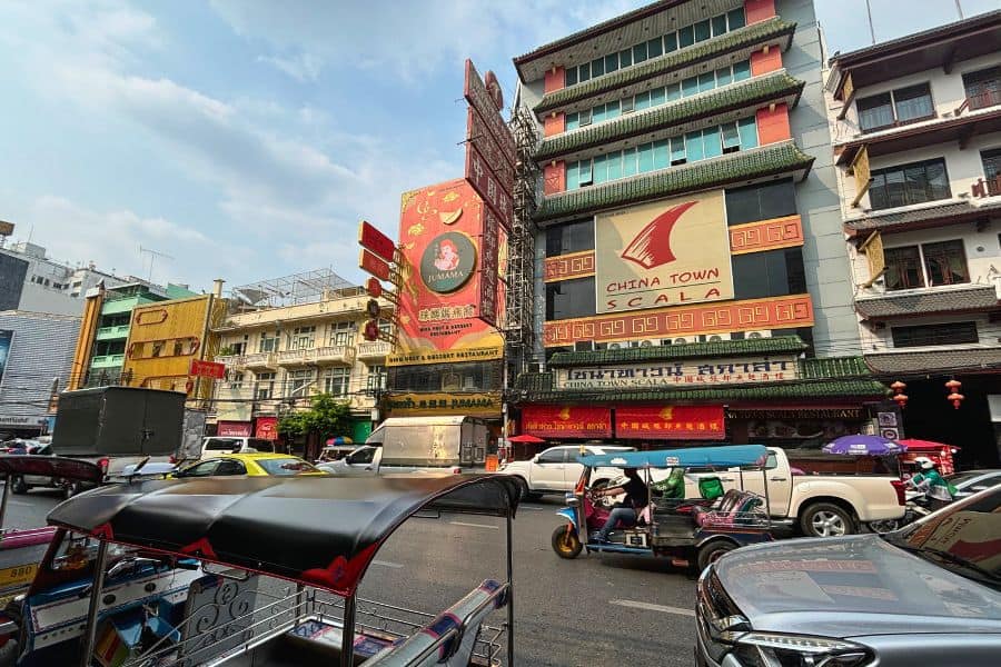 busy street scene in chinatown, bangkok with colorful signs, tuk-tuks, and traffic