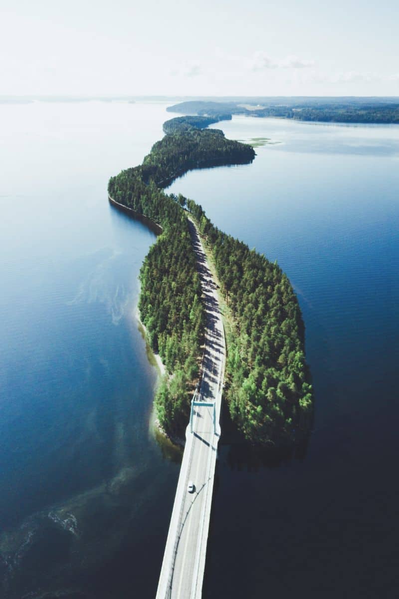 aerial view of the scenic Pulkkilantie road in Asikkala, Finland, winding through narrow forested islands surrounded by the serene blue waters of the Finnish Lakeland