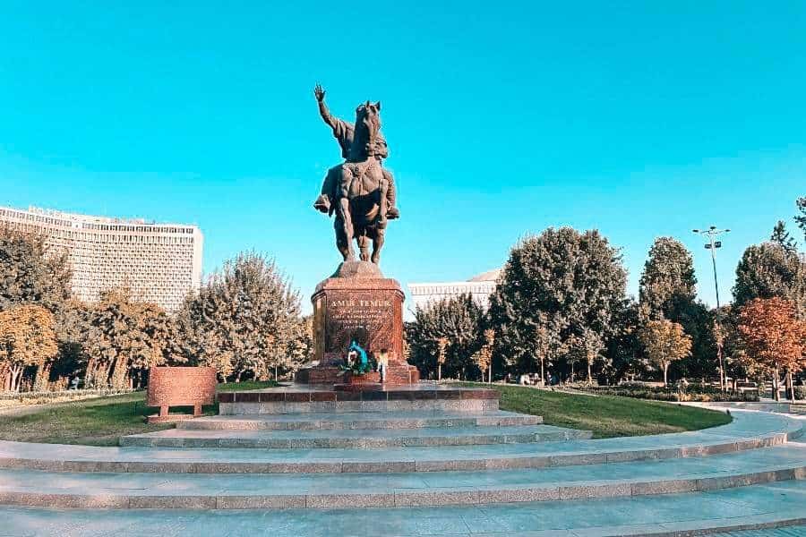 amir temur statue on horseback at amir temur square in tashkent surrounded by trees and modern buildings under clear blue sky