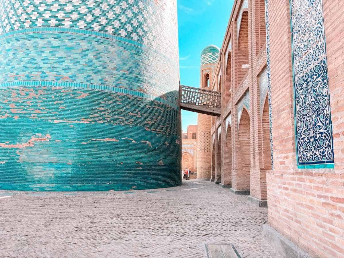 turquoise-tiled minaret and brick walls in khiva, uzbekistan under a clear blue sky