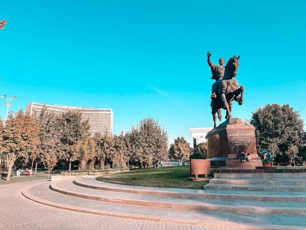 amir temur statue on horseback at amir temur square in tashkent with hotel uzbekistan visible in the background under a clear blue sky