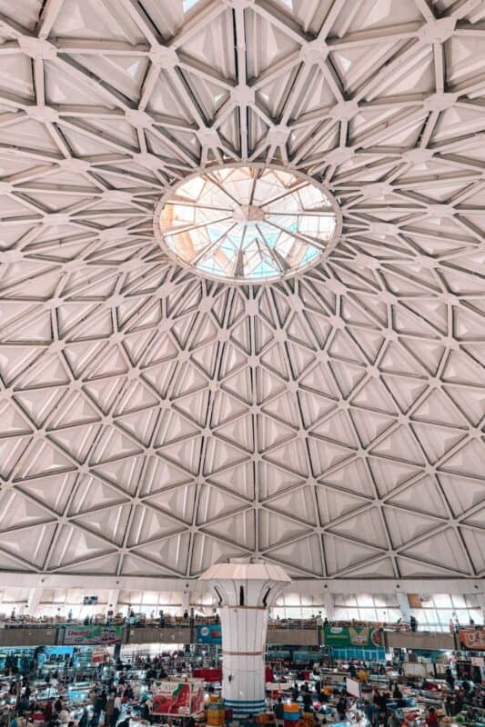 inside view of chorsu bazaar in tashkent, showing the massive domed ceiling with geometric patterns and the bustling market below filled with vendors and shoppers
