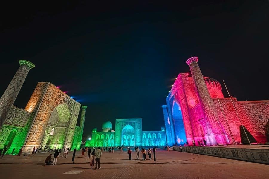 registan square illuminated in colorful lights during the evening light show in samarkand