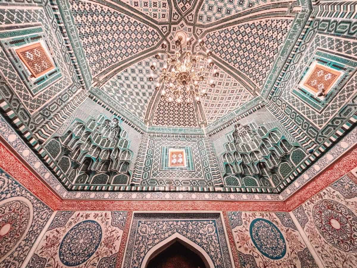intricate interior ceiling of the memorial museum of islam karimov in samarkand, uzbekistan, decorated with turquoise geometric tilework, ornate floral patterns, and a central chandelier