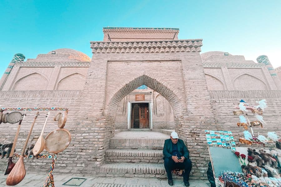 entrance of qozi kalon madrasa in itchan kala khiva with brick archway and handicraft stalls outside