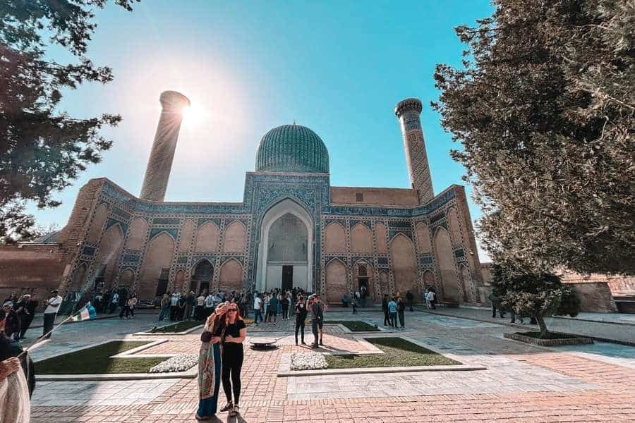 gur-e-amir mausoleum in samarkand with turquoise dome and visitors in the courtyard