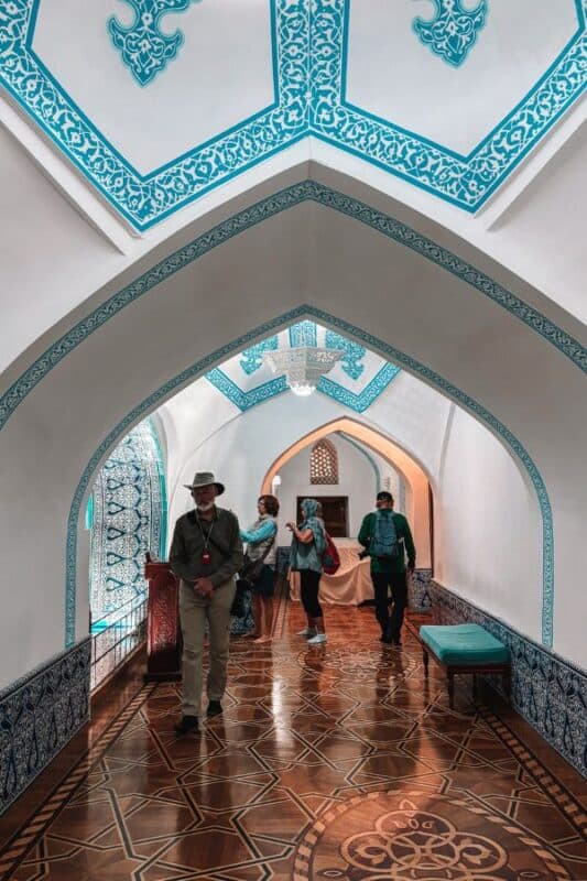 interior hall of pakhlavan mahmud mausoleum khiva with blue tilework arches and wooden patterned floor
