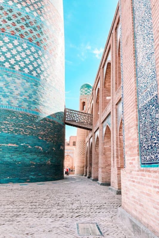 narrow alley between kalta minor minaret and madrasa in itchan kala khiva with blue tiles and brick arches