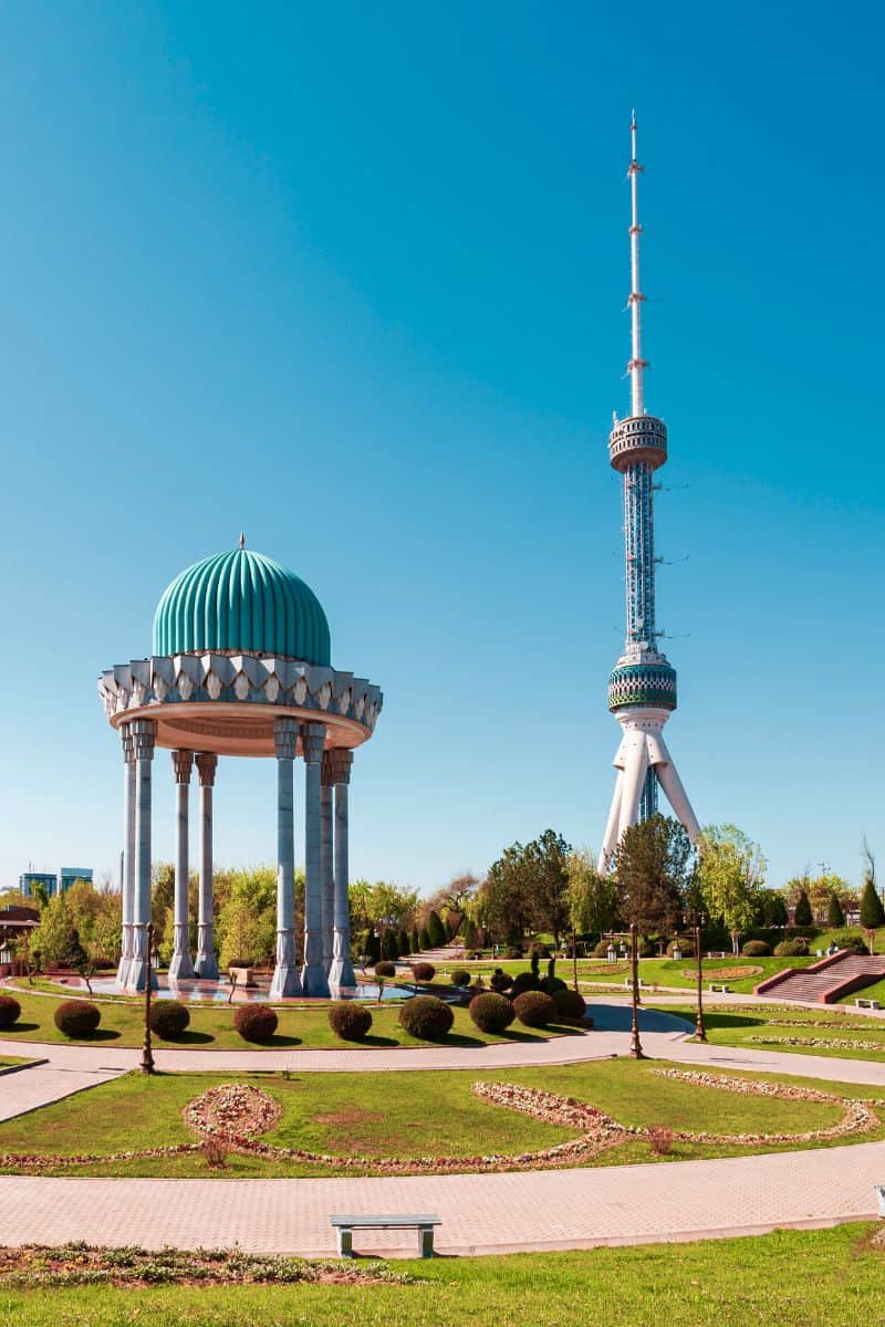 memorial of the victims of repression with the blue-domed rotunda and tashkent tv tower in the background under a clear blue sky