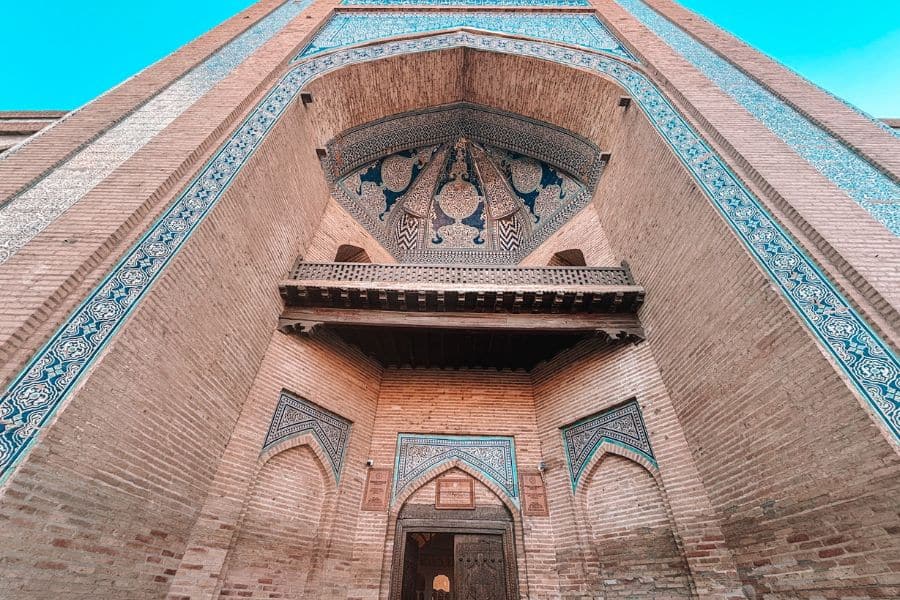 entrance of muhammad amin khan madrasa in itchan kala khiva with blue tilework and carved wooden balcony