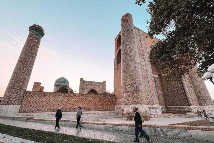 historic islamic architecture in samarkand with tiled minarets and people walking nearby