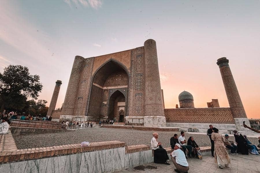 bibi khanum mosque in samarkand with the grand entrance iwan and visitors gathered at sunset