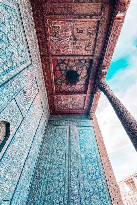 ceiling and tiled walls of tosh hovli palace khiva with carved wooden column and intricate patterns