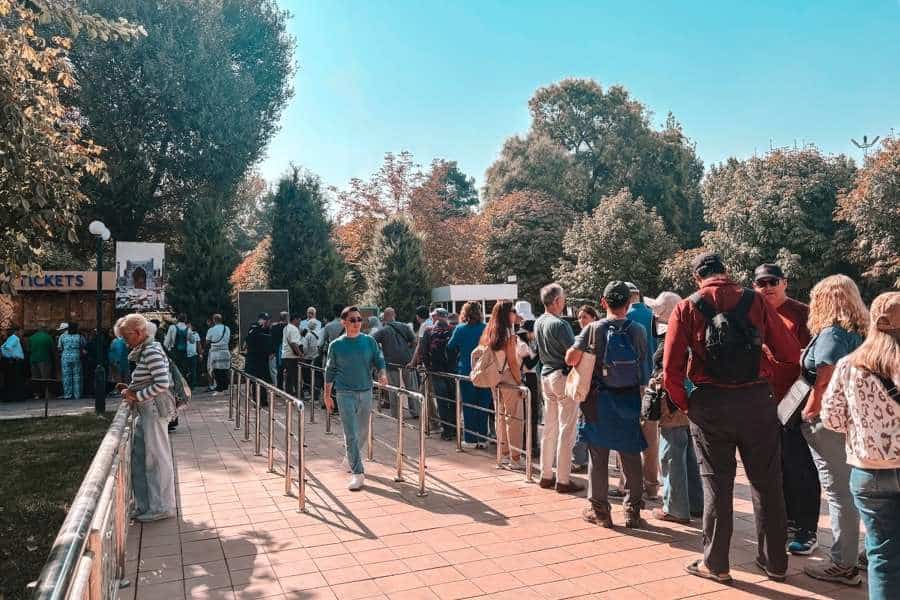 tourist queue at registan ticket counter in samarkand surrounded by trees