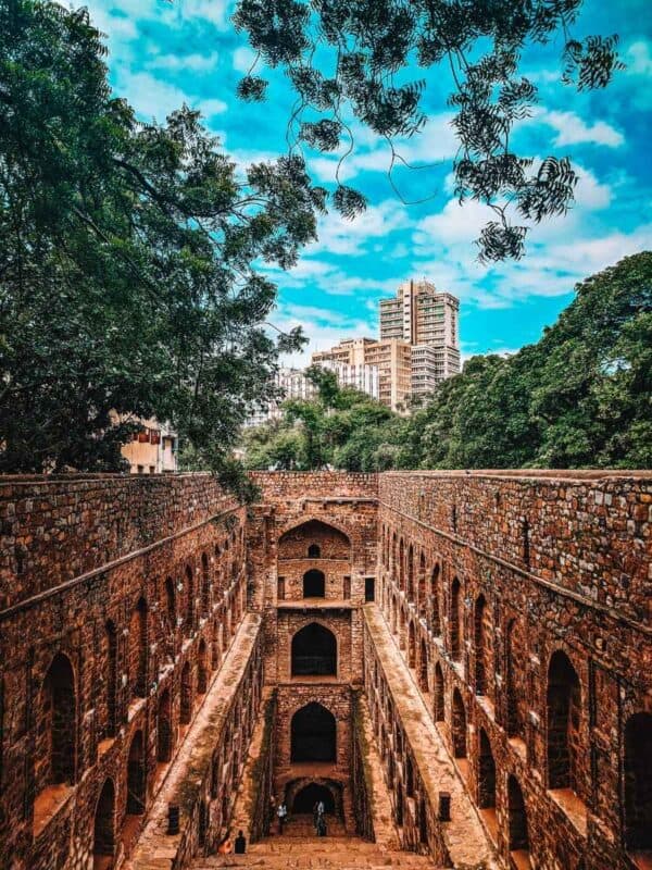 agrasen ki baoli stepwell in delhi with arched walls and city skyline in background