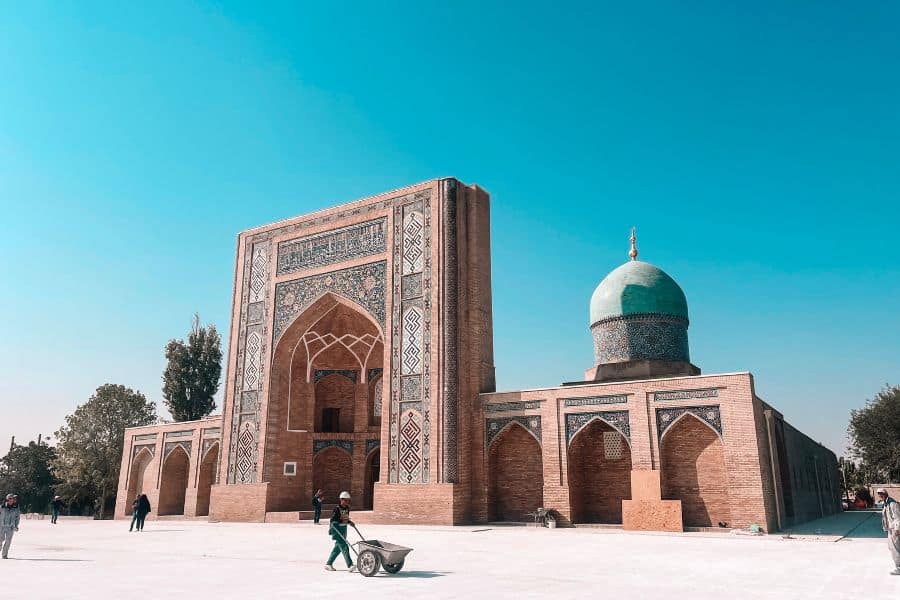barak-khan madrasah at the hazrati imam complex in tashkent, featuring a grand tiled pishtaq and a blue domed mosque under a clear sky