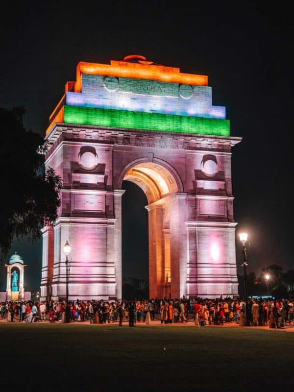 india gate lit up in tricolour at night, surrounded by people