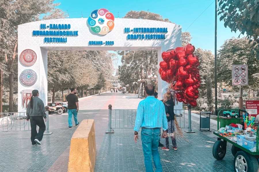 entrance arch of kokand international crafts festival with people walking through