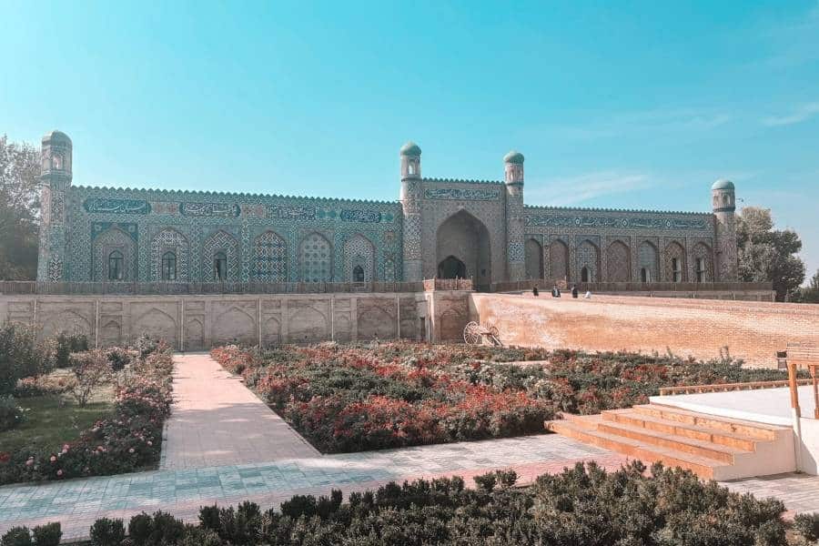 front view of khudoyar khan palace in kokand with garden pathway and blue sky
