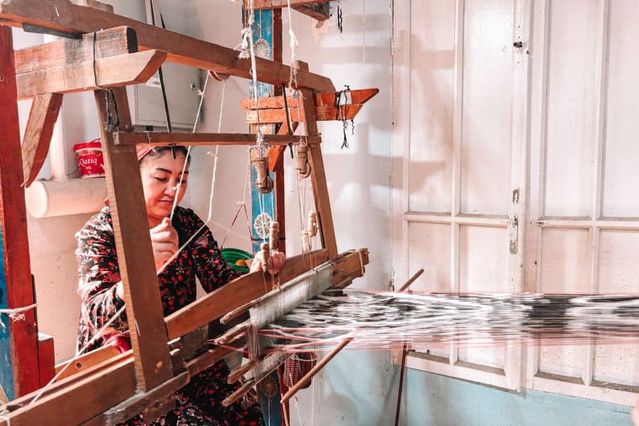 uzbek woman weaving silk fabric on a traditional wooden loom at yodgorlik silk factory in margilan, fergana valley