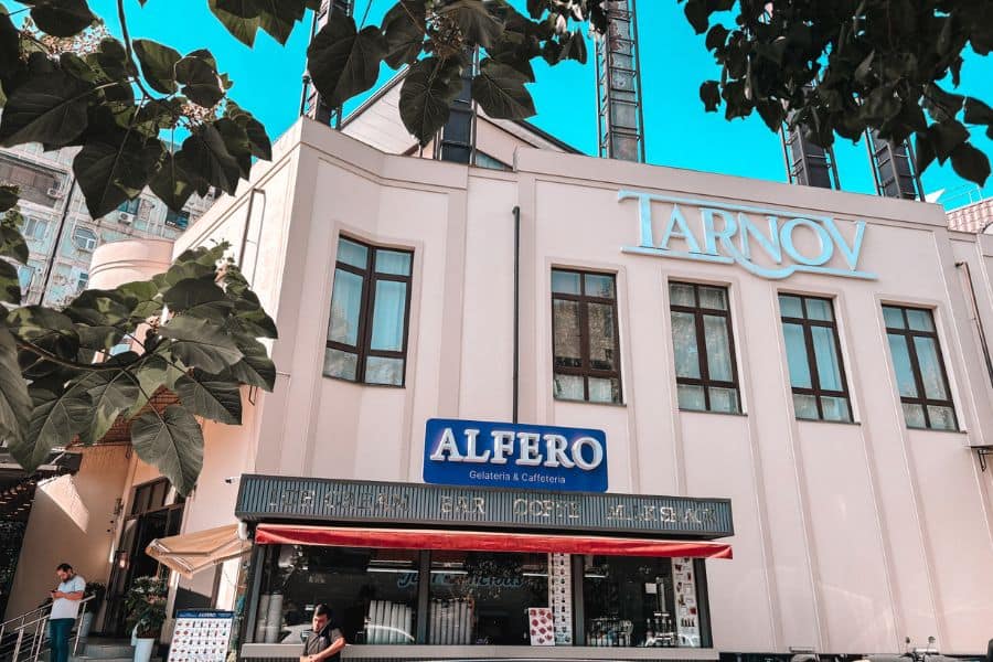tarnov restaurant and alfero gelateria and caffeteria exterior in tashkent with modern white facade and signage, seen through leafy trees