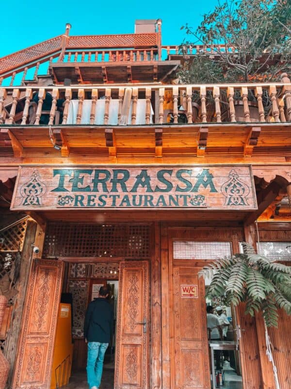 wooden facade of terrassa restaurant in khiva with carved doors and balcony details