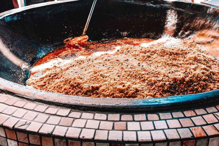 uzbek plov cooking in a large kazan at besh qozon, with rice, meat, and spices simmering over open heat