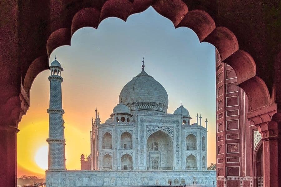 taj mahal at sunrise framed by an arched doorway