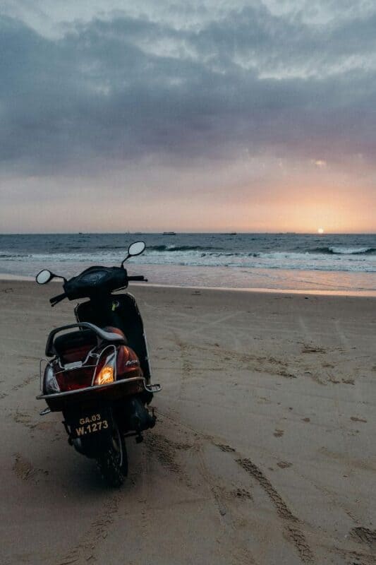 empty beach with a scooter parked in goa india during sunset