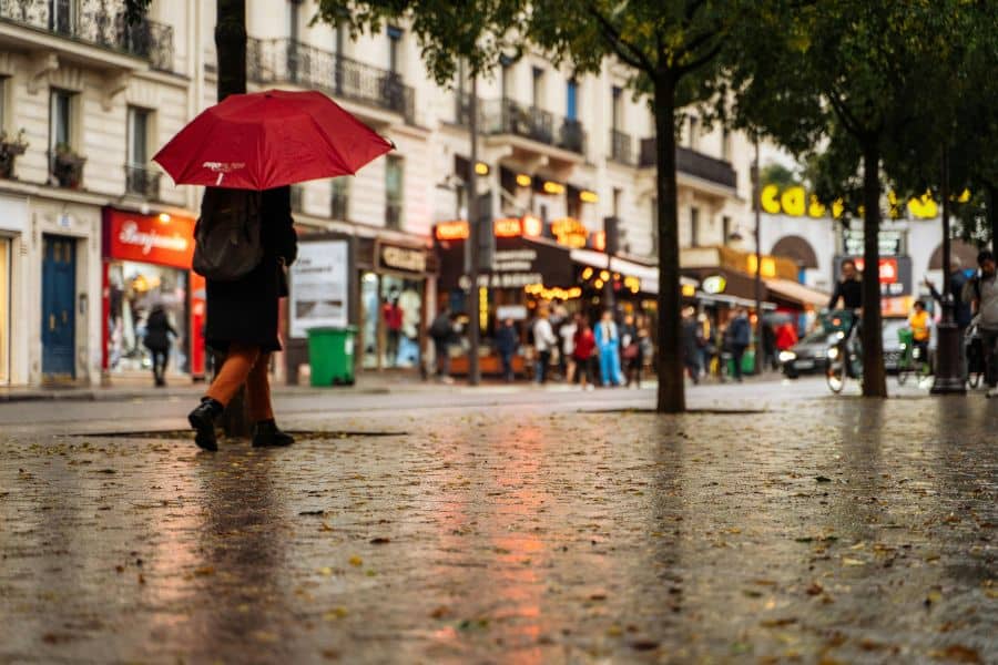 paris street in autumn with wet pavement and red umbrella
