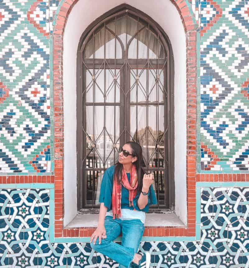 me sitting by the colorful mosaic wall of the khudayar khan palace in kokand uzbekistan