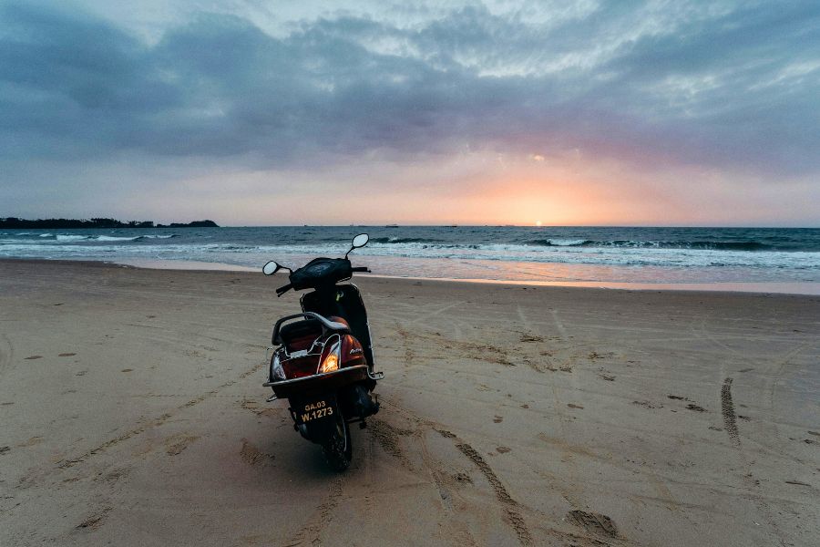 scooter parked on a quiet goa beach at sunset with waves in the background