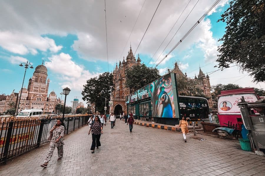 Chhatrapati Shivaji Maharaj Terminus (CST) and BMC Headquarters in Fort, South Mumbai, with pedestrians on the footpath and traffic in the foreground