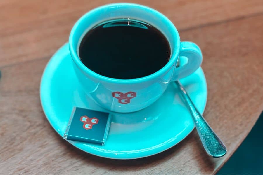 Black coffee in a Kala Ghoda Cafe (KGC) branded turquoise cup with chocolate at Kala Ghoda Cafe, Fort, South Mumbai