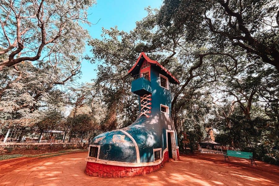 The Old Woman's Shoe house at Kamala Nehru Park on Malabar Hill, Mumbai, a blue boot-shaped structure from the nursery rhyme, surrounded by old trees